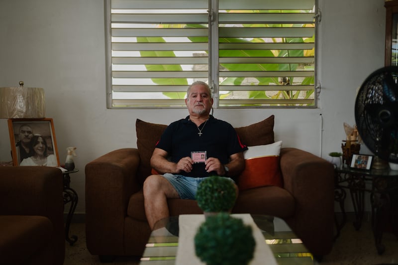 22 de julio de 2024. Salinas, PR. Retrato del exempleado afectado de STI Henry Morales en la sala de su casa en Hacienda La Margarita. En al foto, Henry está con su ID de Steritech. (Foto por Esteban G. Morales Neris | Centro de Periodismo Investigativo/Grist)