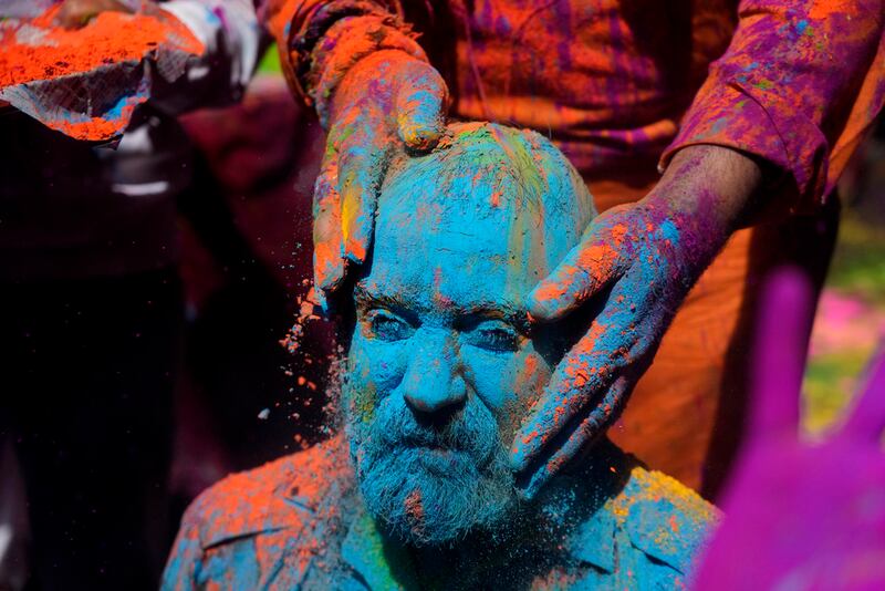 Personas se untan polvos de colores mientras celebran el Holi en Jammu, India.