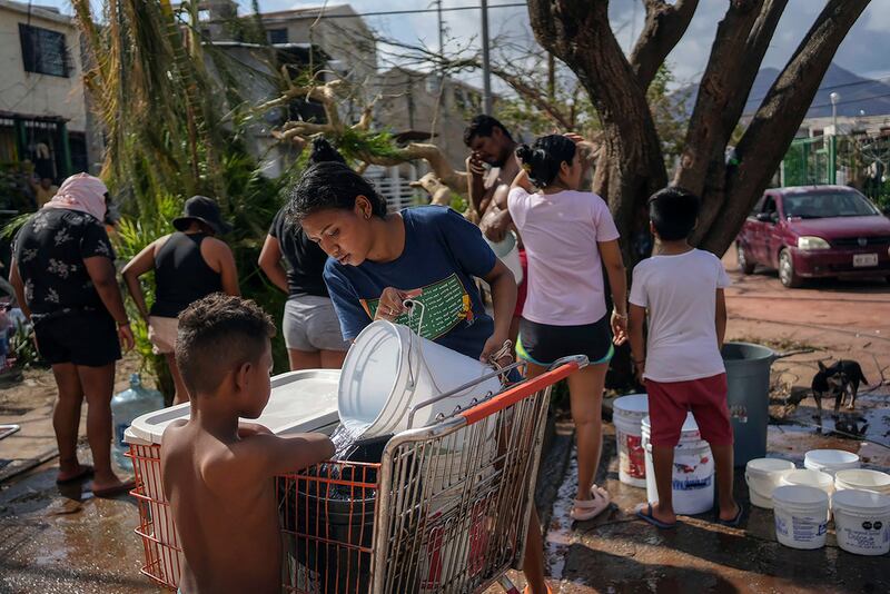 Unos hermanos recolectan agua de un pozo público el viernes 27 de octubre de 2023 tras el paso del huracán Otis en Acapulco, México.
