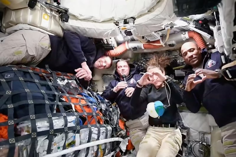 Imagen de un video proporcionado por la NASA muestra al comandante de la tripulación de Artemis II, Reid Wiseman, segundo desde la izquierda, agradeciendo a las familias de la tripulación mientras hablaba con el Control de Misión de la NASA en una videoconferencia durante el viaje rumbo a la Luna. El astronauta canadiense y especialista de misión Jeremy Hansen, a la izquierda, observa la escena, mientras que la especialista de misión Christina Koch y el piloto Victor Glover, a la derecha, forman corazones con las manos. (NASA via AP)