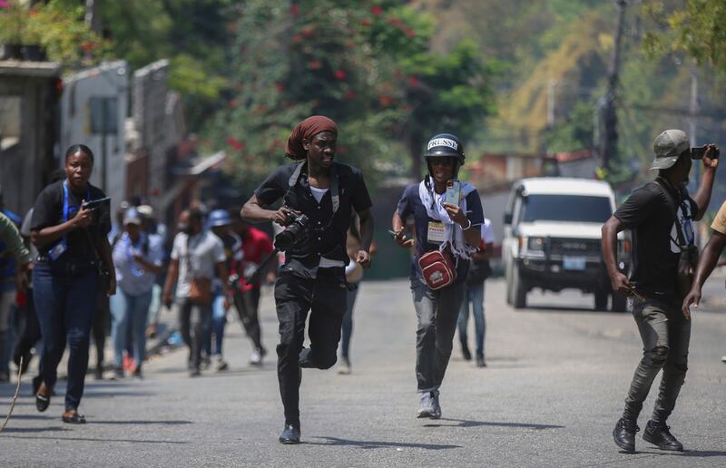 Periodistas corren a refugiarse mientras manifestantes lanzan piedras a un coche de policía durante una protesta en Puerto Príncipe, Haití, el 19 de marzo de 2025. (Foto AP/Odelyn Joseph, Archivo)