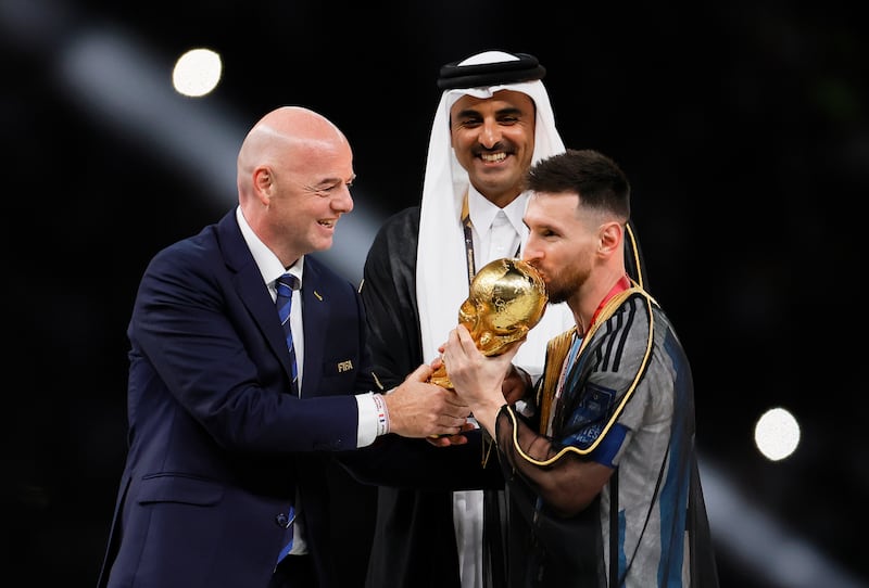 Lusail (Qatar), 18/12/2022.- Lionel Messi (R) of Argentina receives the trophy from FIFA president Gianni Infantino (L) and Sheikh Tamim bin Hamad Al Thani (C), the Emir of Qatar, after winning the FIFA World Cup 2022 Final between Argentina and France at Lusail stadium in Lusail, Qatar, 18 December 2022. Argentina won 4-2 on penalties. (Mundial de Fútbol, Francia, Estados Unidos, Catar) EFE/EPA/Ronald Wittek