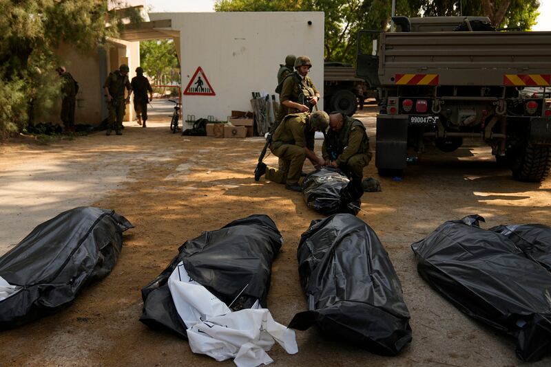 Soldados israelíes junto a cadáveres de ciudadanos israelíes asesinados por militantes de Hamas en kibbutz Kfar Azza el martes.
