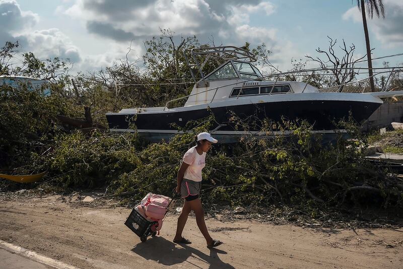 Una residente lleva varios artículos personales que salvó tras el impacto del huracán Otis en Acapulco.
