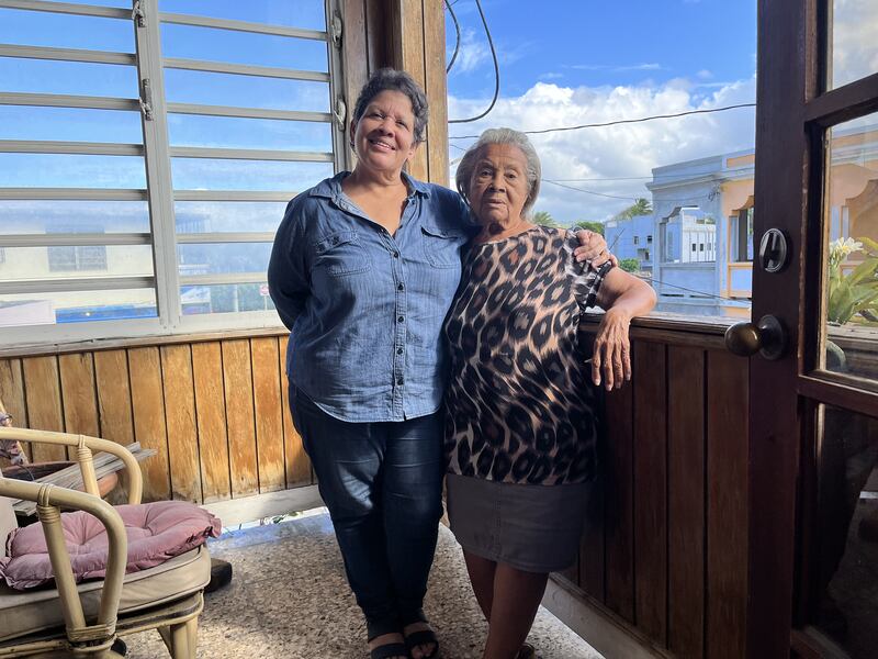 Gloria Ramírez Escobar acompaña a su madre Gloria Escobar Skerett, de 87 años, quien se niega a vender su casa en Luquillo. Es la única familia luquillense que se mantiene en esta línea de la calle Fernández García, en el casco del pueblo.