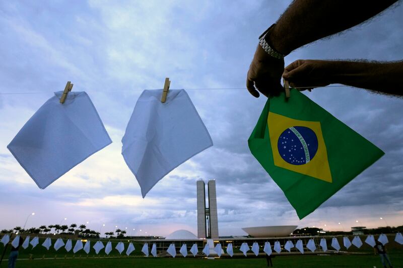 Pañuelos blancos que representan a personas que han muerto por Covid-19 en Brasil cuelgan sobre un campo para protestar por las políticas de salud del gobierno, frente al Congreso en Brasilia, Brasil.