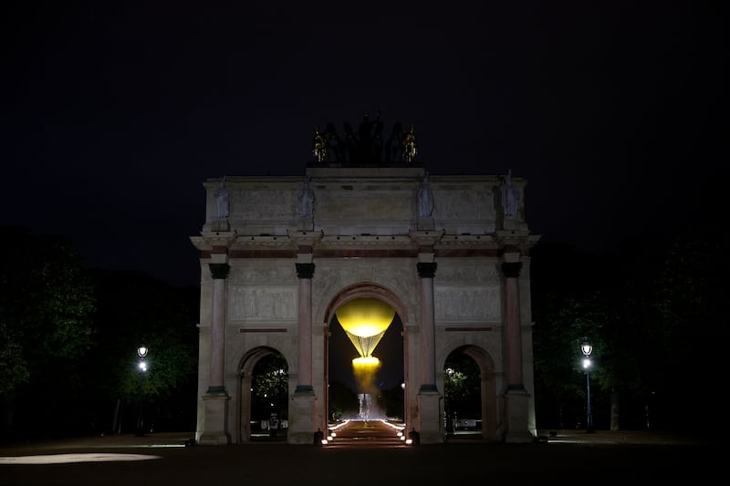 PARIS, FRANCE - JULY 26: A general view of through the Arc de Triomphe du Carrousel as Torch bearers French Athlete Marie-Jose Perec and French Judo Practitioner Teddy Riner (obscured) look on as the Olympic Cauldron lifts into the sky after being lit at the Gardens of the Tuileries during the opening ceremony of the Olympic Games Paris 2024 on July 26, 2024 in Paris, France. (Photo by Adam Pretty/Getty Images)