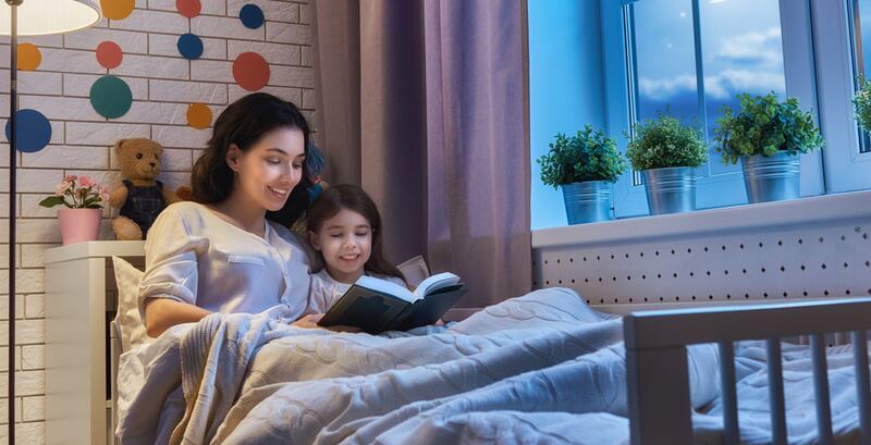 Family reading bedtime. Pretty young mother reading a book to her daughter.