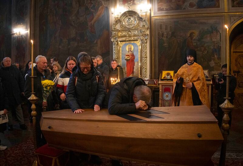 Dos padres de familia lloran sobre el ataúd de Oleksandr Grianyk del regimiento Azov a quien mataron el 8 de mayo defendiendo la ciudad de Mariúpol de los invasores rusos, durante un funeral en la Catedral de San Miguel en Kyiv, Ucrania, el 14 de enero de 2023. Los restos de Grianyk fueron identificados recientemente. (Foto AP/Efrem Lukatsky)