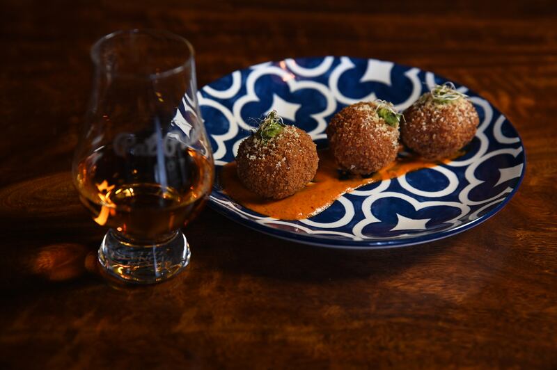 Arancinis sobre una base de salsa infusionada con whisky.
