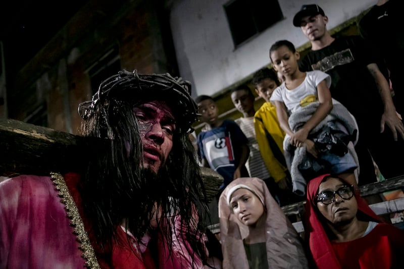 Luiz Henrique (izquierda), que interpreta el papel de Jesucristo, carga con la cruz durante una recreación del Via Crucis dentro de la celebración de la Semana Santa en la favela Complexo do Alemao, en Río de Janeiro, Brasil, el 29 de marzo de 2024. La Semana Santa conmemora los últimos días de la vida de Jesús, según la Biblia, incluyendo su crucifixión el Viernes Santo y su resurrección en el Domingo de Pascua. (AP Foto/Bruna Prado)