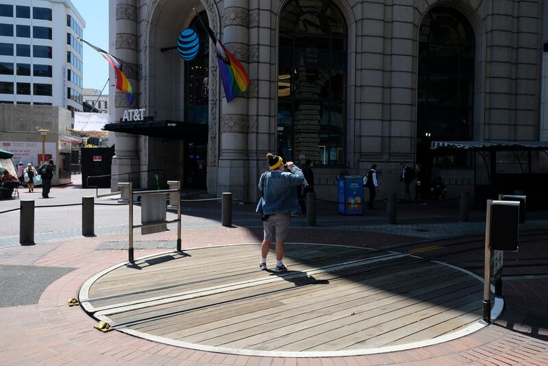 Un hombre vapea en el giro de un teleférico vacío en las calles Powell y Market en San Francisco, el 21 de junio de 2023. En el fondo está la tienda insignia de AT&T que recientemente anunció su cierre.