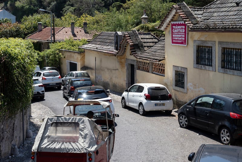 Tráfico pesado en una calle estrecha en Sintra, donde un cartel lee 