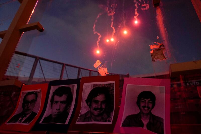 Fuegos artificiales iluminan el cielo ante un despliegue de retratos de personas que fueron ejecutadas y desaparecidas en los primeros días de la dictadura militar del general Augusto Pinochet, durante una vigilia por el 50mo aniversario del golpe militar de 1973, el lunes 11 de septiembre de 2023, en Santiago.