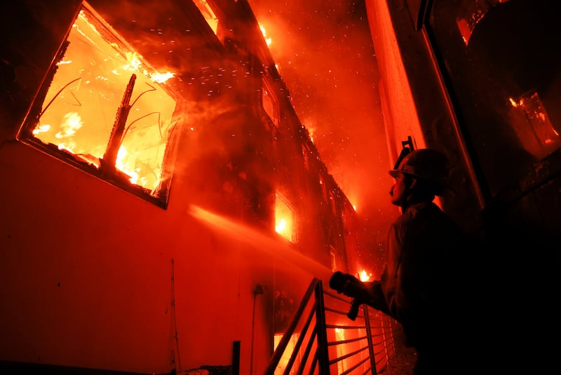 ARCHIVO - Un bombero trabaja desde una terraza mientras el incendio Palisades quema una propiedad frente a la playa el 8 de enero de 2025 en Malibú, California. (Foto AP/Etienne Laurent, Archivo)