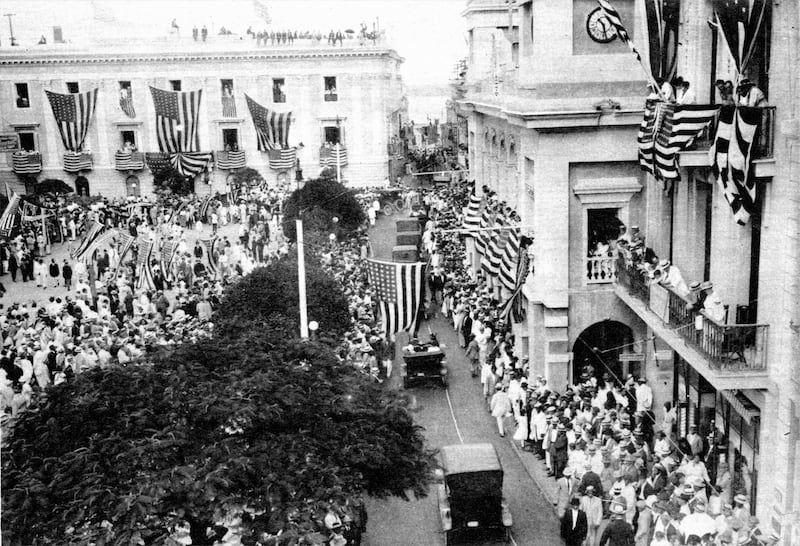 vista de la Plaza de Armas y la Calle San Francisco durante una celebración del 4 de julio, posiblemente en 1920. Fue publicada en la página 17 de la revista The Mentor de enero de 1921 que dedicó ese número a Puerto Rico.