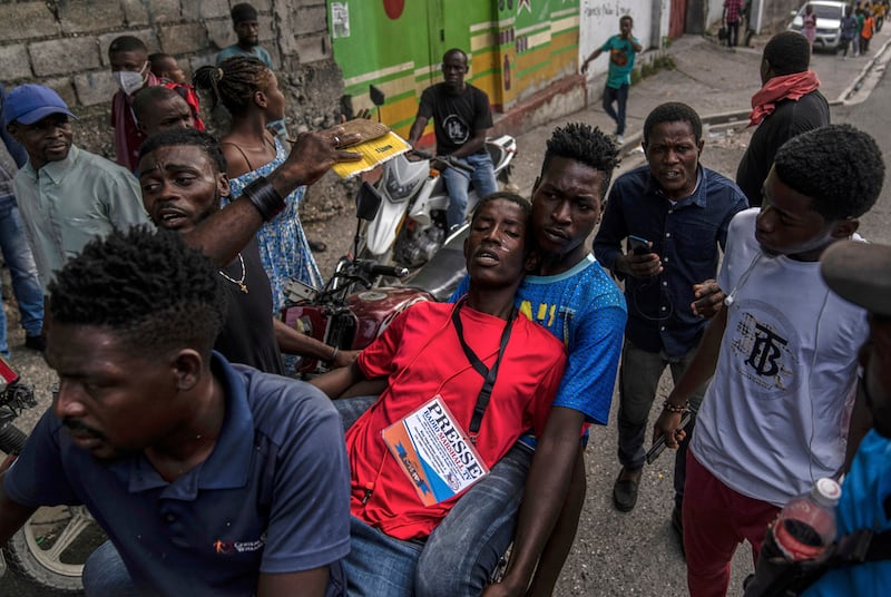 ARCHIVO - Un grupo de personas ayuda a un periodista que resultó afectado por gas lacrimógeno lanzado por policías durante una protesta por la muerte del periodista Romelson Vilsaint, en Puerto Príncipe, Haití, el 30 de octubre de 2022. (AP Foto/Ramon Espinosa, archivo)
