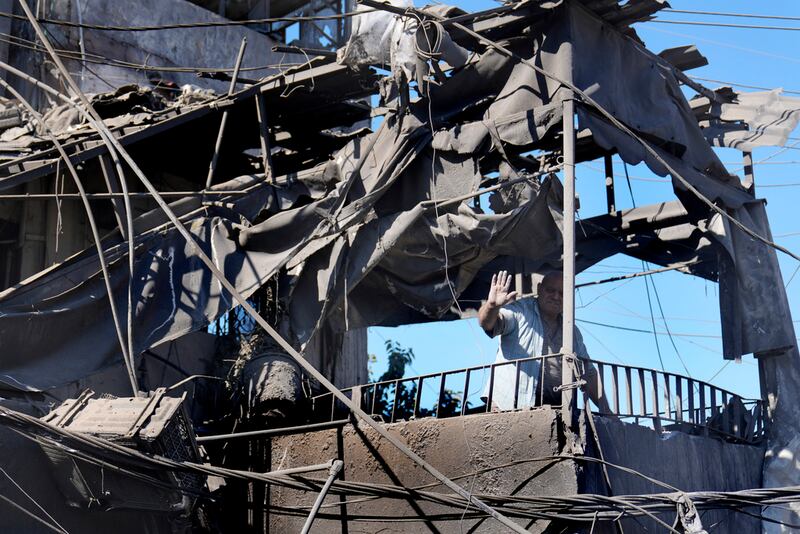 Un hombre saluda desde su casa destrozada en el lugar de los ataques aéreos israelíes que destruyeron los edificios frente al principal hospital gubernamental de la ciudad, en un barrio densamente poblado, en el sur de Beirut, Líbano, el martes 22 de octubre de 2024. (Foto AP/Hussein Malla)