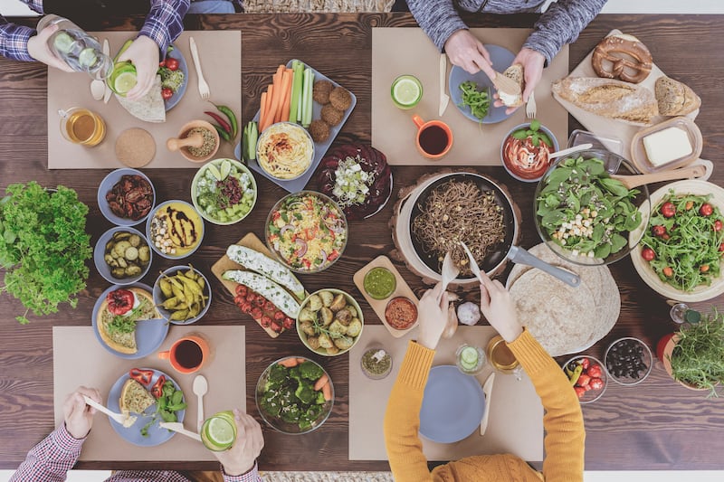 Vegetarian family eating healthy vegetable dinner by communal table