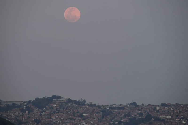A full moon rises above the Petare neighborhood of Caracas, Venezuela, Sunday, May 15, 2022. People in the Americas, Europe and Africa will see the total lunar eclipse during the night of May 15-16. (AP Photo/Matias Delacroix)