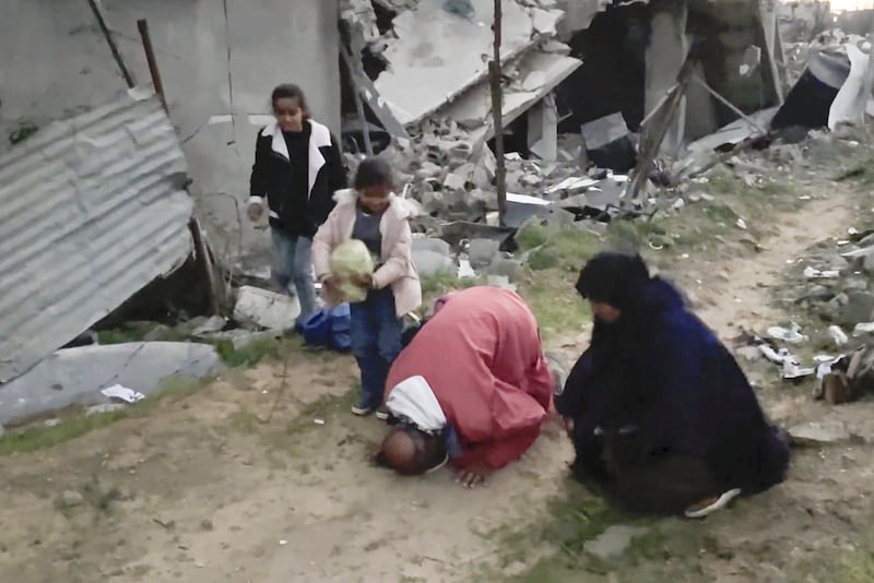 Ne'man Abu Jarad besa la tierra tras llegar junto a su familia a su casa en Beit Lahiya, en la Franja de Gaza el lunes. Es la primera vez que regresan desde que comenzó la guerra entre Israel y Hamás. (AP Photo)
