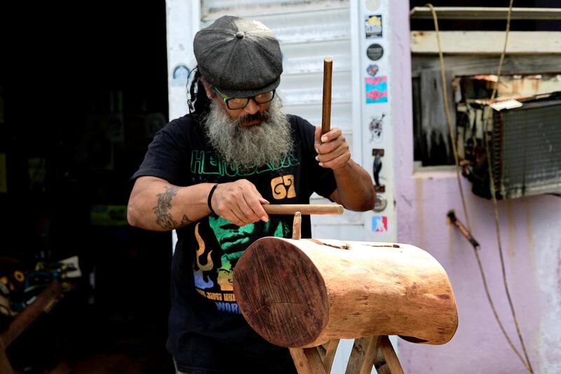 Manny Vázquez toca percusión sobre un tronco de madera durante una entrevista con EFE en su taller este lunes, en Manatí. EFE/ Thais Llorca
