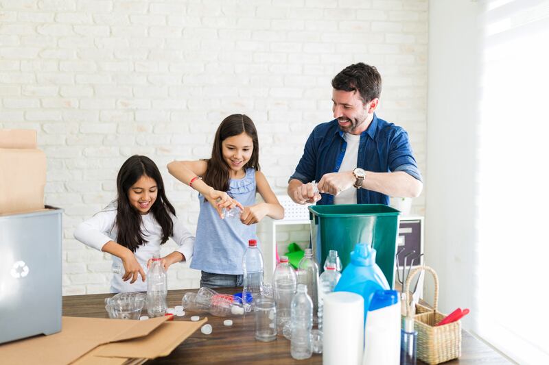 Familia latina de tres compactando botellas para prevenir daño ambiental