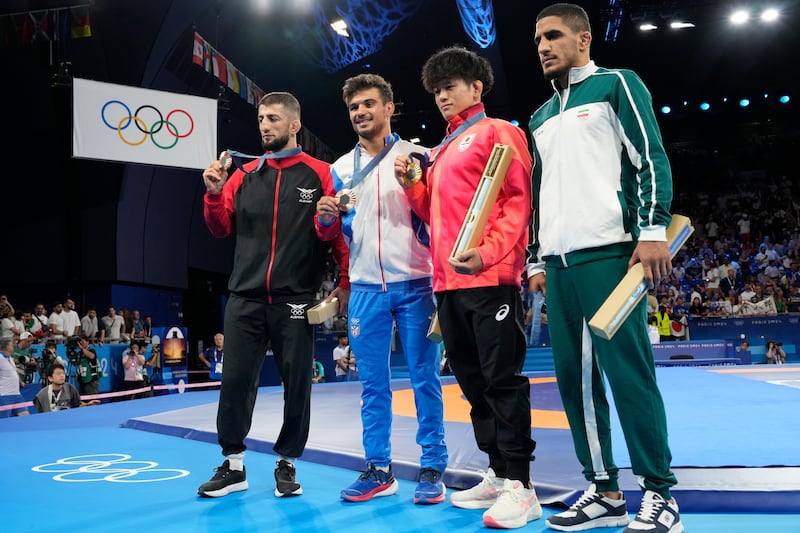 Los medallistas, de izquierda a derecha, Islam Dudaev de Albania, Sebastian Rivera de Puerto Rico (bronce), Kotaro Kiyooka de Japón (oro) y Rahman Amouzadkhalili de Irán (plata), posan durante la ceremonia de entrega de medallas de lucha libre masculina de 65 kg en el Champ-de-Mars Arena durante los Juegos Olímpicos de París 2024, el domingo 11 de agosto de 2024, en París, Francia. (Foto AP/Eugene Hoshiko)