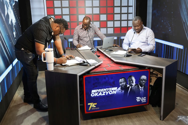Los periodistas haitianos Johnny Ferdinand (izquierda), Guerrier Dieuseul (centro) y Ronald Desormes (derecha) trabajan en el noticiero matutino desde el estudio de la emisora ​​Radio TV Caraibe en el barrio de Petion-ville, Puerto Príncipe, Haití, el jueves 20 de marzo de 2025. (Foto AP/Odelyn Joseph)
