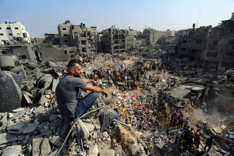 Un hombre se sienta sobre los escombros mientras otros buscan entre los restos de edificios atacados por la aviación israelí, en el campo de refugiados de Jabaliya, en el norte de la Franja de Gaza.