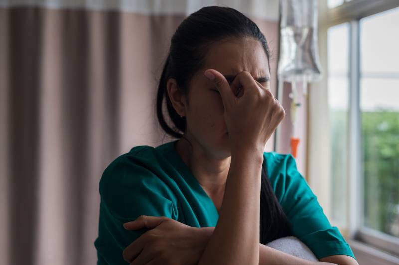 Una enfermera se coloca el la mano cerrada en su rostro reflejando frustración.