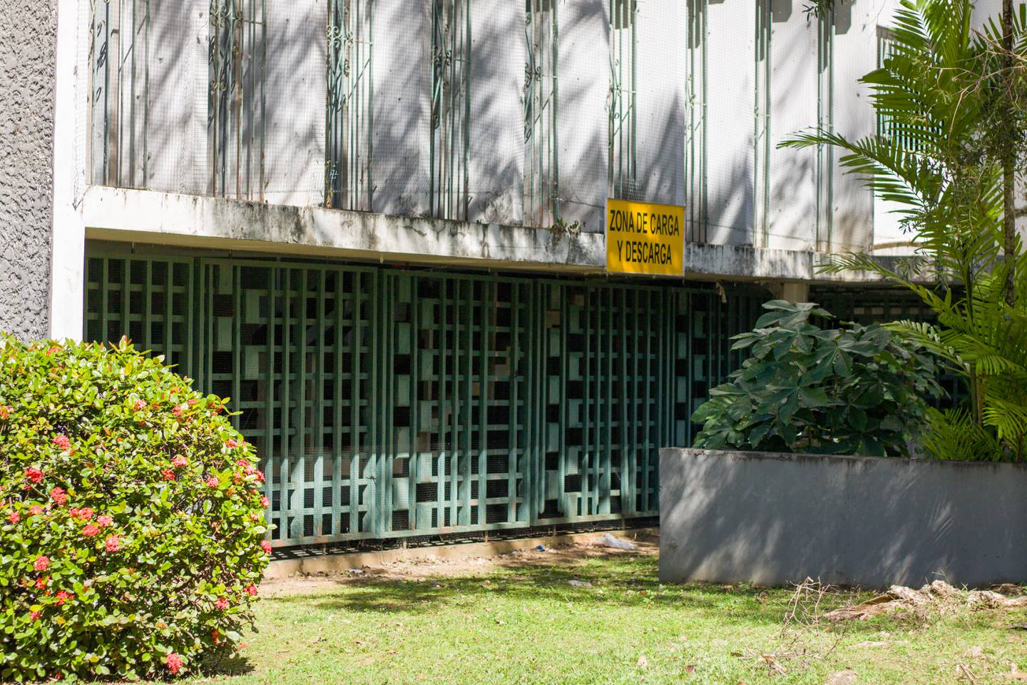 Unos portones verdes sellan el primer piso de ResiCampus bajo un letrero amarillo que lee "Zona de carga y descarga".