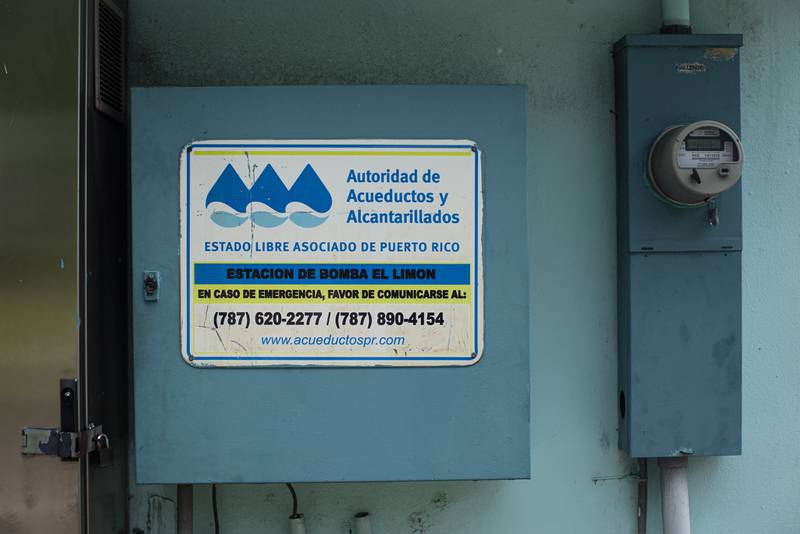 En un cajón color azul, en una pared junto a un contador, tiene un cartel de la Autoridad de Acueductos y Alcantarillados que lee "Estación de bomba El Limón".