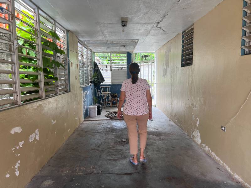 Mujer caminando en su hogar, la cual se encuentra en pobres condiciones.