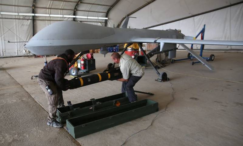 Trabajadores subcontratados cargan un misil Hellfire en un vehículo aéreo no tripulado (UAV) Predator MQ-1B de la Fuerza Aérea de EE UU.