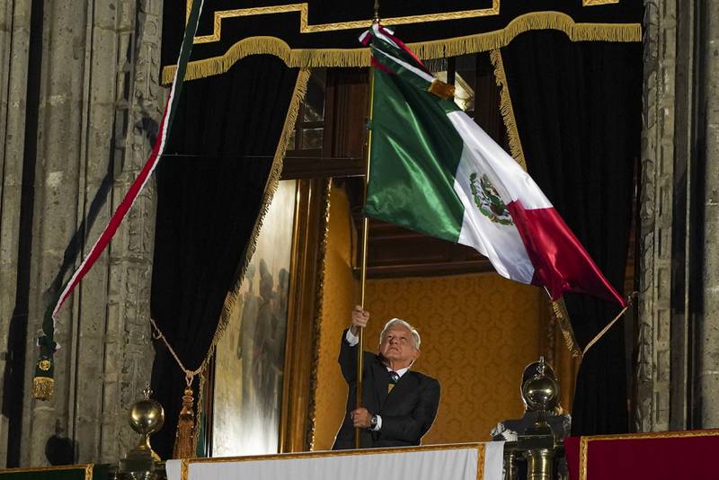 El presidente de México, Andrés Manuel López Obrador, ondea la bandera nacional tras el llamado "Grito de Independencia" que da comienzo a los festejos de la independencia mexicana, en un balcón del Palacio Nacional, en la Plaza del Zócalo de la Ciudad de México, el 15 de septiembre de 2023. (AP Foto/Marco Ugarte)