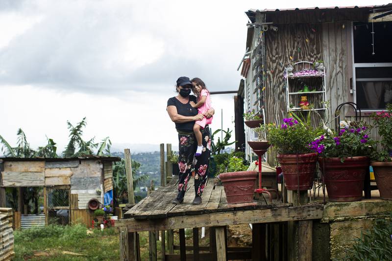 Virgen Báez sostiene a su nieta a las afueras de su hogar.