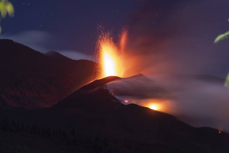 Un volcán en erupción. Se observa el cielo oscuro y una fuente de magma surgiendo de la boca de un volcán.