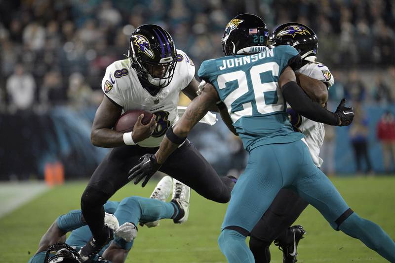 El quarterback de los Ravens de Baltimore Lamar Jackson intenta avanzar con el balón frente al safety de los Jaguars de Jacksonville en el encuentro del domingo 17 de diciembre del 2023. (AP Foto/Phelan M. Ebenhack)