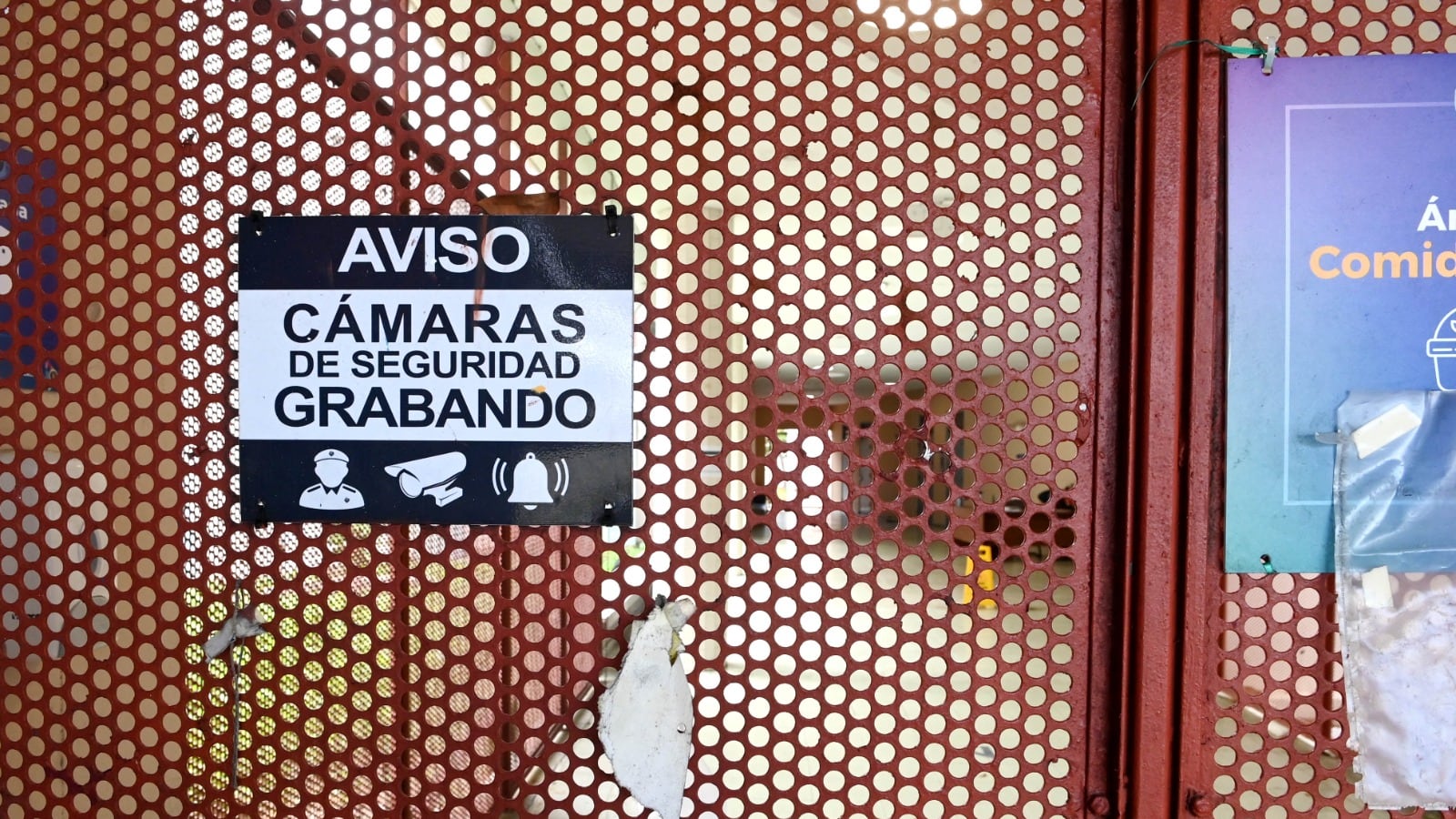 El portón de una escuela con un letrero que lee "aviso, cámaras de seguridad grabando".