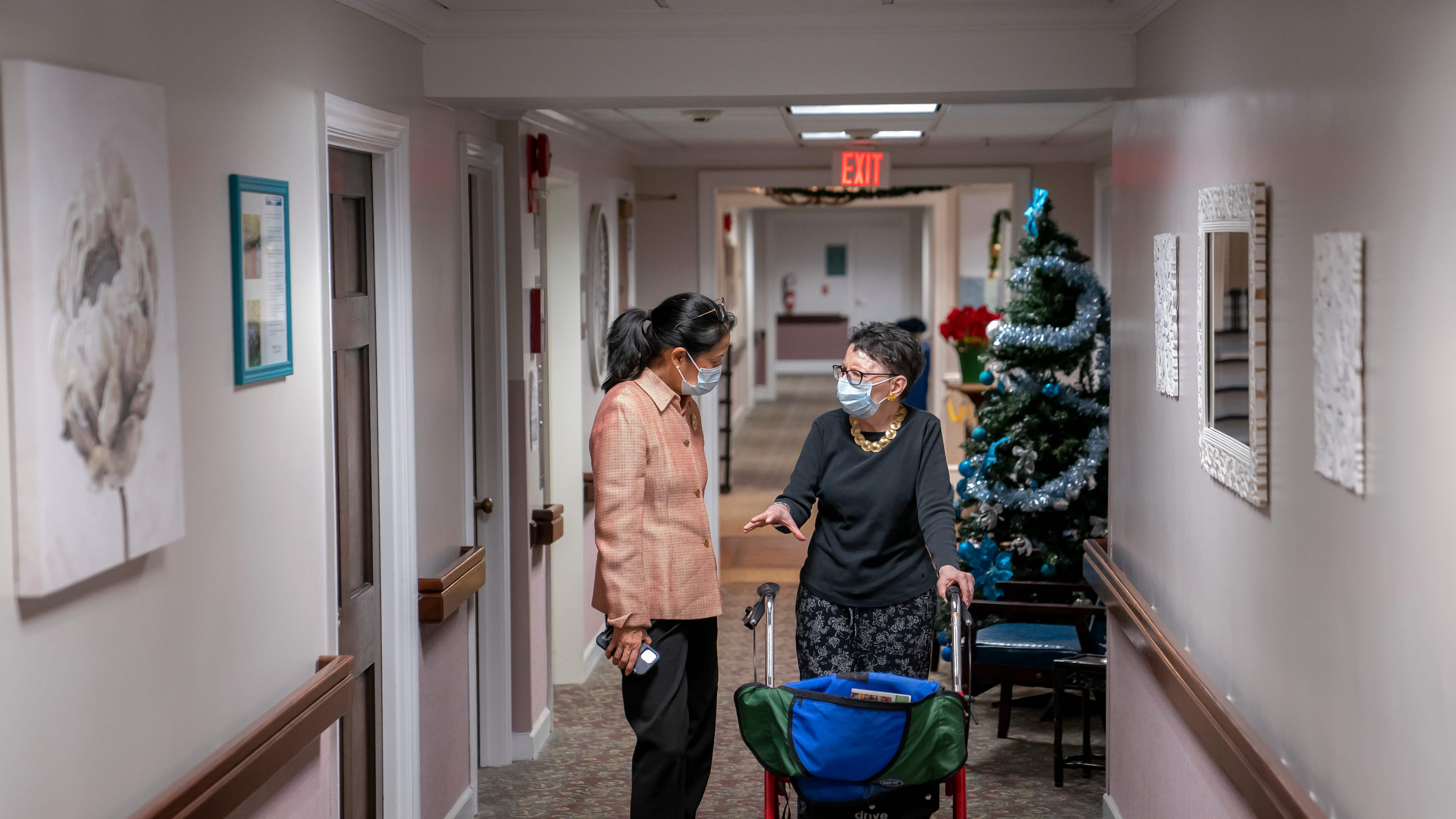 ARCHIVO - Tina Sandri, CEO de la residencia para ancianos Forest Hills of DC, izquierda, ayuda a la residente Courty Andrews a regresar a su habitación, 8 de diciembre de 2022, en Washington. El gobierno del presidente Joe Biden dictará por primera vez los niveles mínimos de dotación de personal de las residencias para ancianos en respuesta a los problemas sistémicos que salieron a la luz con las muertes masivas provocadas por el COVID-19, se informó el viernes 1 de setiembre de 2023. (AP Foto/Nathan Howard, File)