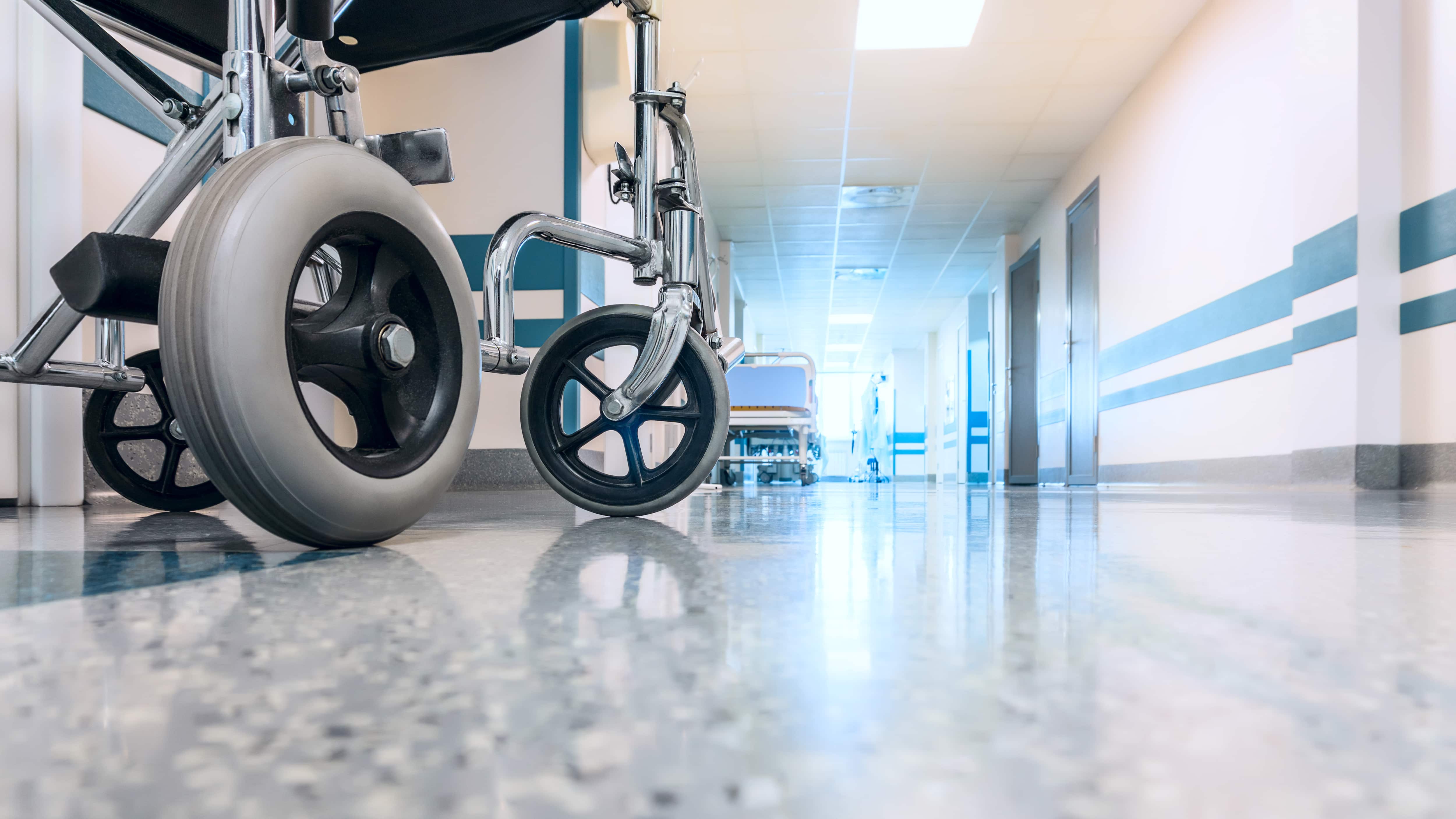 Una silla de ruedas vacía estacionada en el pasillo de un hospital.