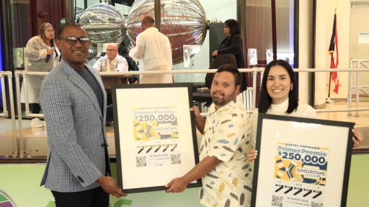 Carlos Calderón Ayala, subdirector de la Lotería Tradicional, entrega el billete conmemorativo a Stephanie Ávila Berríos, directora ejecutiva de la Fundación Puertorriqueña de Síndrome Down.