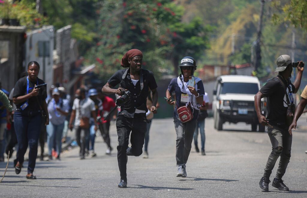 Periodistas corren a refugiarse mientras manifestantes lanzan piedras a un coche de policía durante una protesta en Puerto Príncipe, Haití, el 19 de marzo de 2025. (Foto AP/Odelyn Joseph, Archivo)