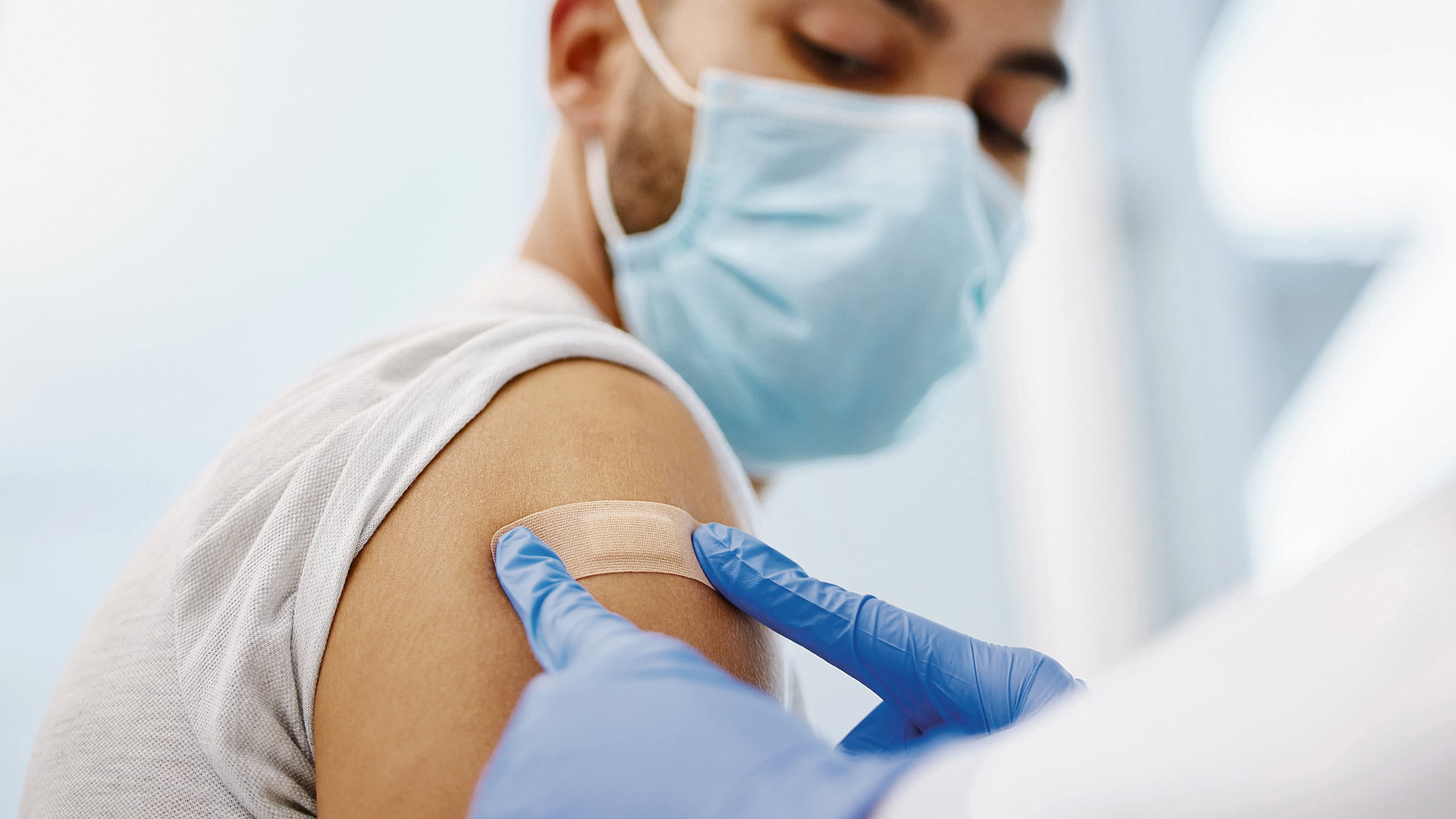 Le colocan una curita a un joven en el brazo después de ponerle una vacuna.