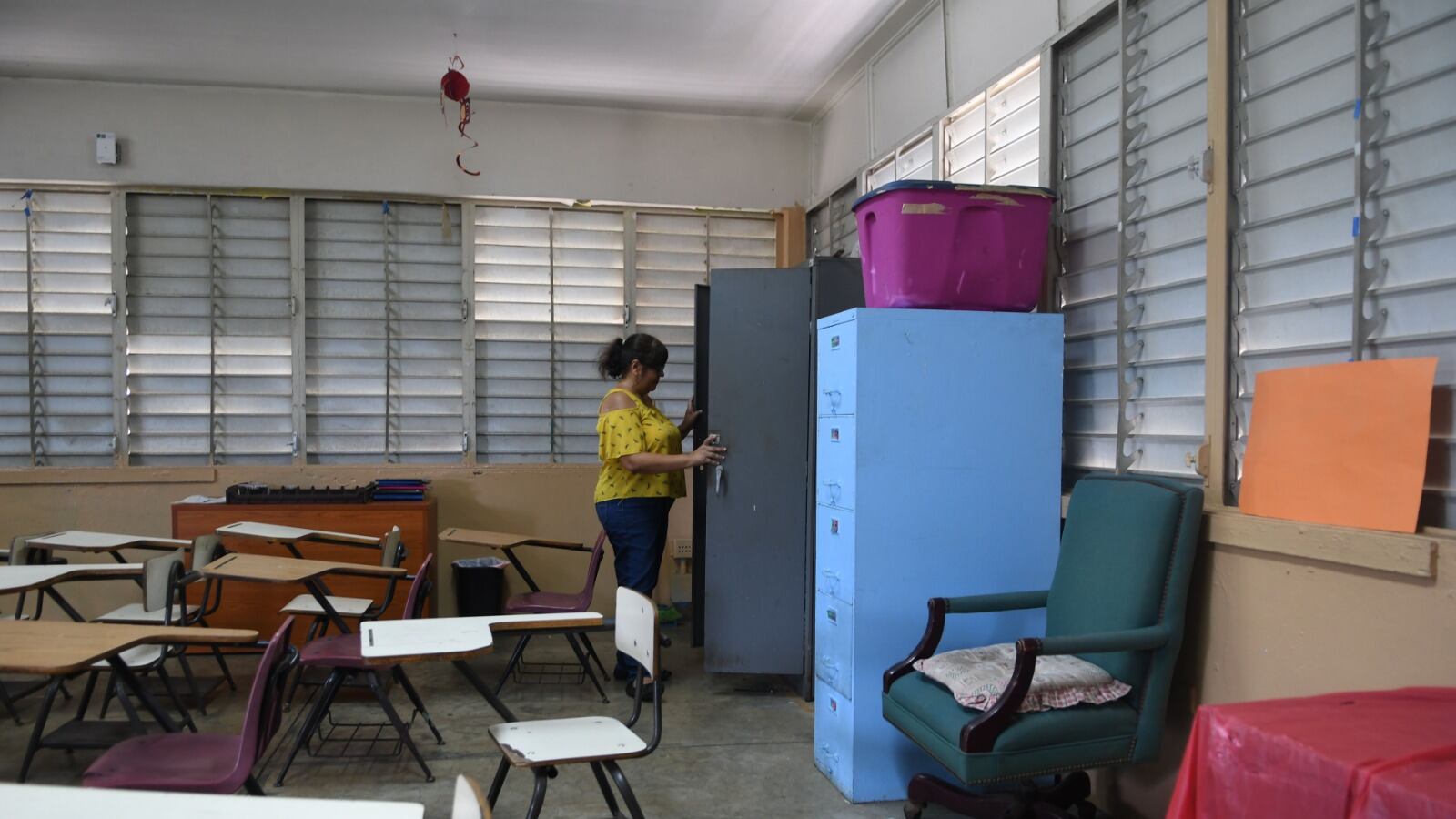 Una maestra mira dentro de un estante en busca de materiales.