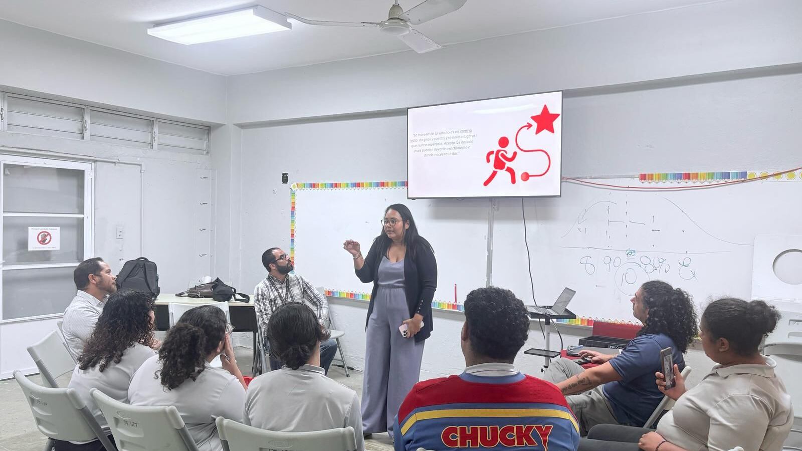 Investigadora ofrece charla a jóvenes sentados en sillas blancas.