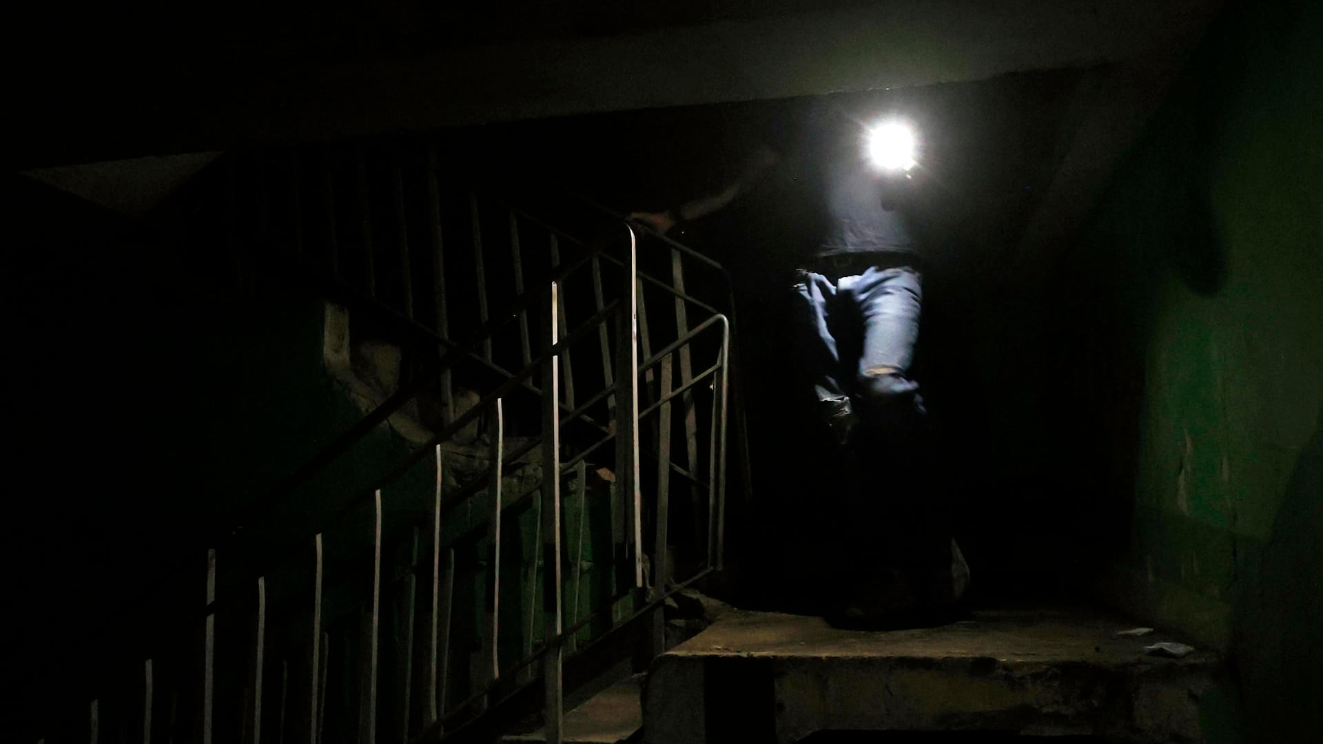 Fotografía de archivo de una persona que baja las escaleras mientras alumbra con un teléfono en La Habana (Cuba). EFE/ Ernesto Mastrascusa