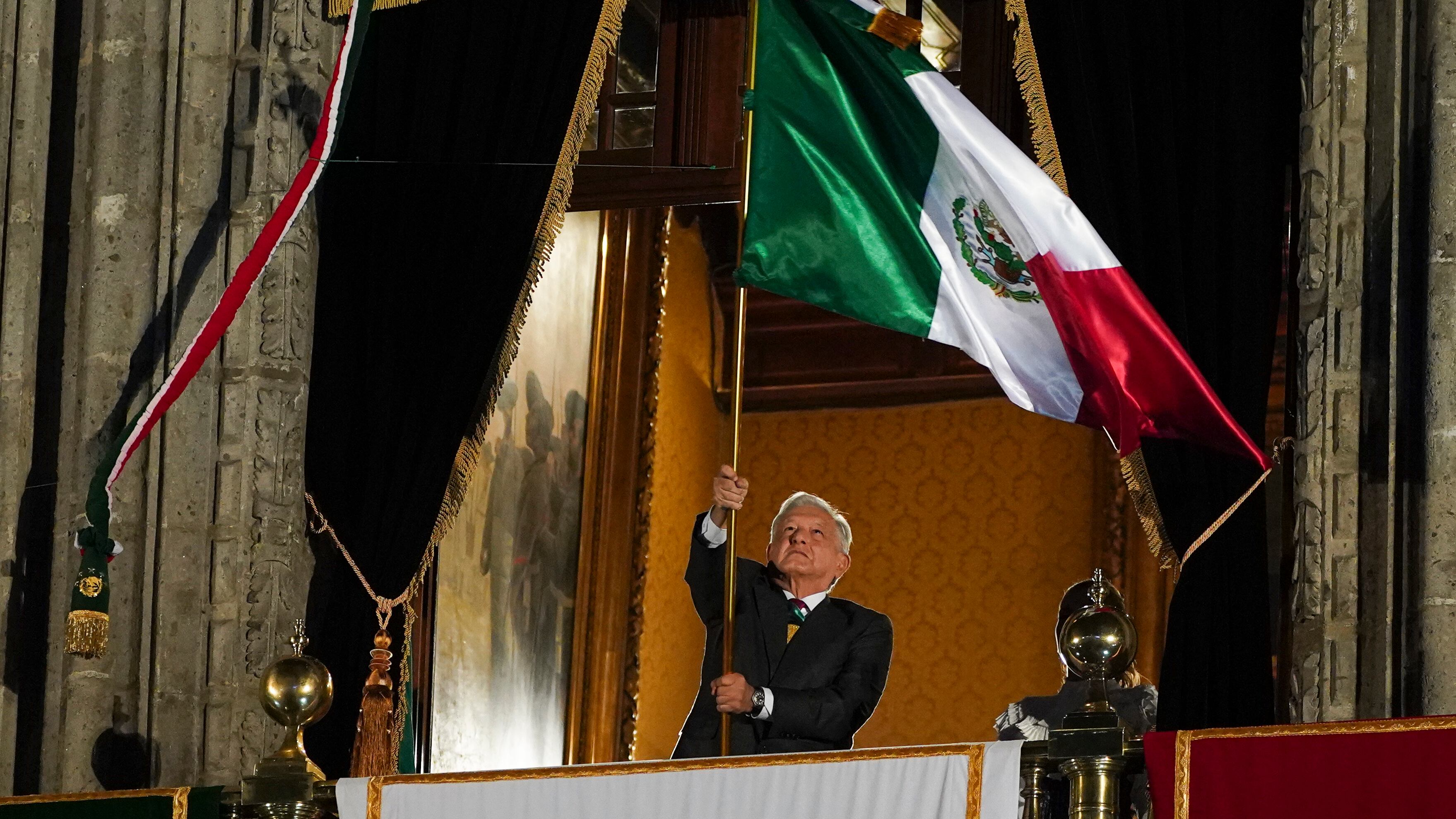 El presidente de México, Andrés Manuel López Obrador, ondea la bandera nacional tras el llamado "Grito de Independencia" que da comienzo a los festejos de la independencia mexicana, en un balcón del Palacio Nacional, en la Plaza del Zócalo de la Ciudad de México, el 15 de septiembre de 2023. (AP Foto/Marco Ugarte)
