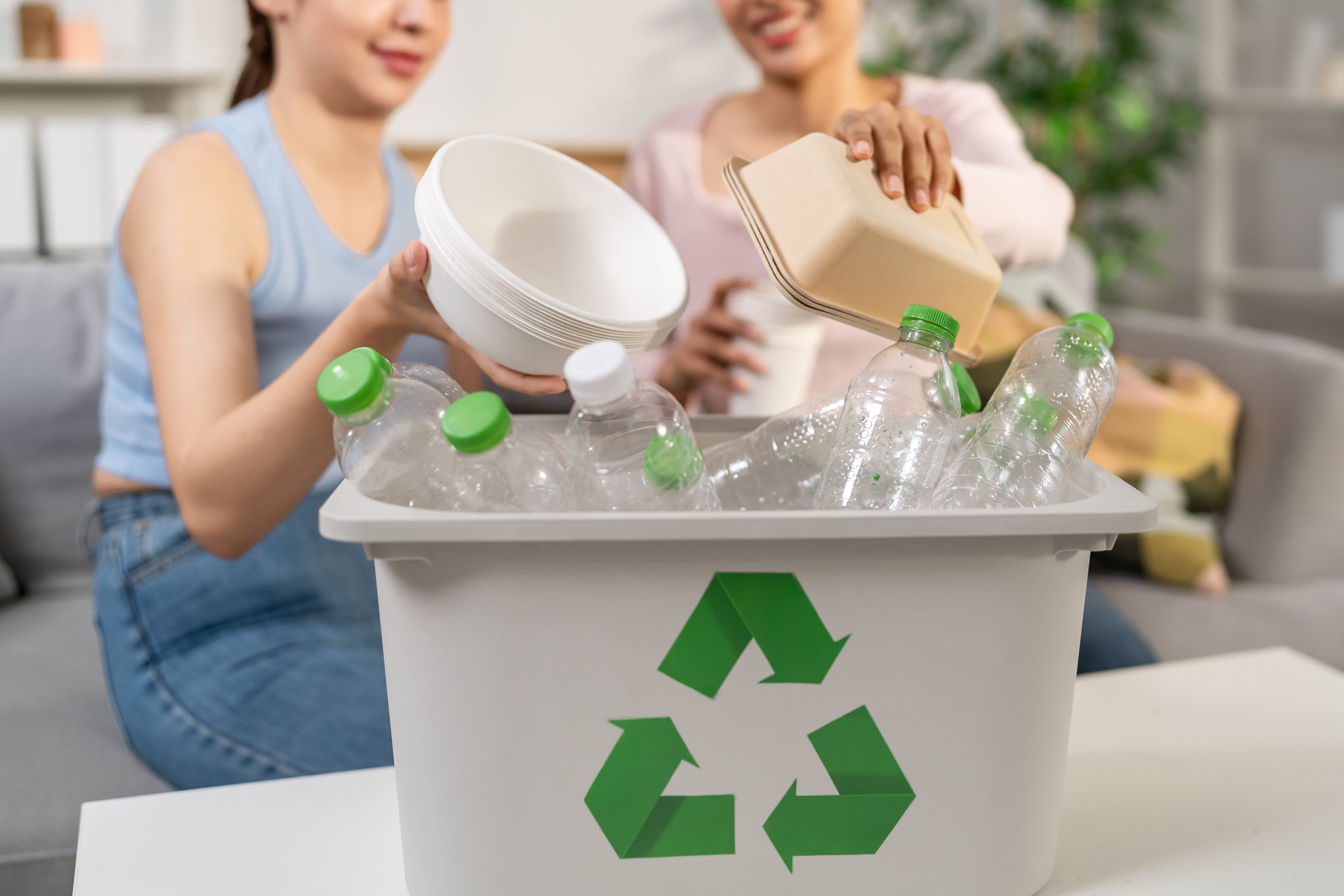 Dos jóvenes clasifican residuos en diferentes contenedores, simbolizando cómo las acciones diarias de cada persona, por pequeñas que sean, se suman para generar un impacto significativo en la consecución del ODS 12: Producción y Consumo Responsables.